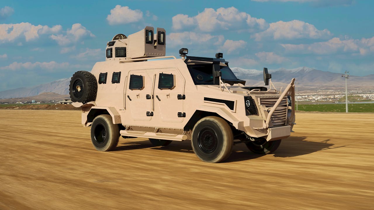 An armored military vehicle drives on a dirt road with mountain backdrop in Kurdistan.