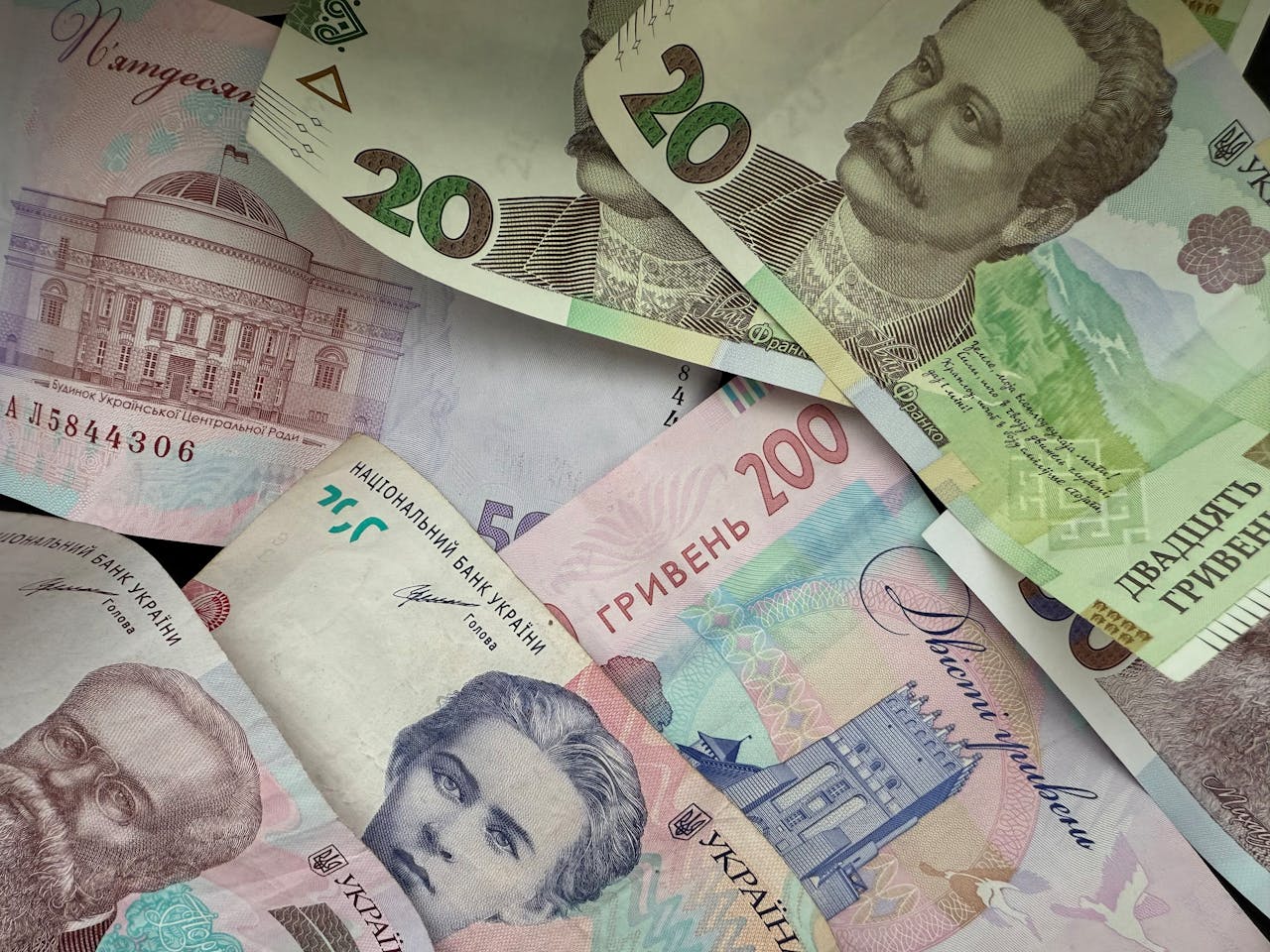 A vibrant assortment of Ukrainian Hryvnia banknotes featuring historical figures and architecture.